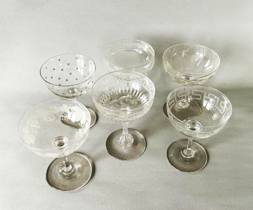 fig 3. A harlequin set of six clear Victorian glass champagne coupes featuring varied etched motifs including starbursts and Greek key patterns.