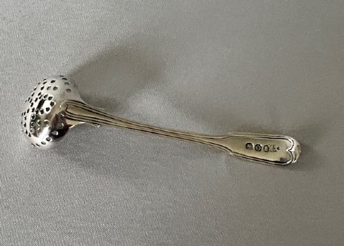 A Georgian sterling silver spice sifting spoon featuring a circular pierced bowl and a long moulded handle. View IV