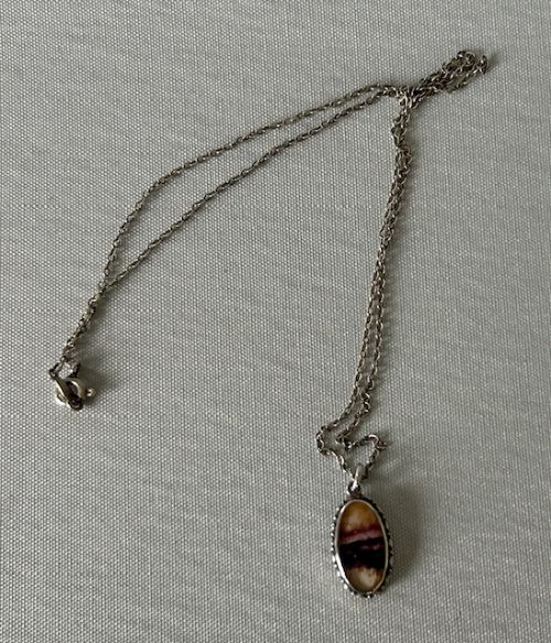 fig 1. An oval Art Deco silver pendant featuring a banded purple and cream Blue John stone suspended from a silver trace chain.