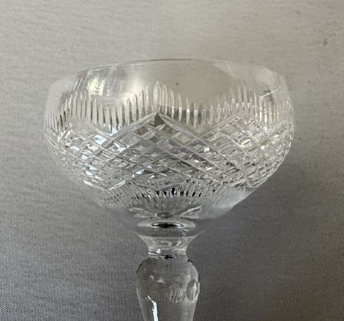 A set of six clear cut glass champagne coupes featuring faceted stems and diamond-cut bowls arranged on a neutral background. View V