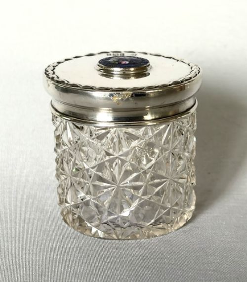 A round cut glass vanity jar topped with a hallmarked sterling silver lid featuring a central blue floral enamel motif. View III