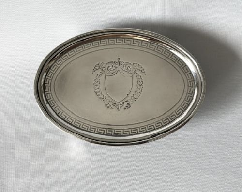 fig 1. An oval Georgian silver teapot stand featuring an engraved Greek key border, a central cartouche, and four small supportive feet.