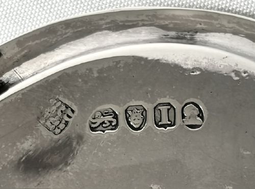An oval Georgian silver teapot stand featuring an engraved Greek key border, a central cartouche, and four small supportive feet. View V