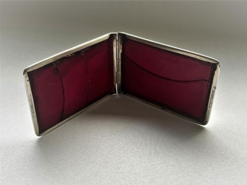fig 1. A rectangular Edwardian sterling silver wallet and stamp case displaying visible British silver hallmarks on its smooth metallic exterior.