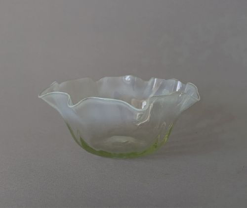 fig 1. A small yellowish-green vaseline glass finger bowl featuring a flared ruffled rim with white opalescent shading.