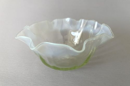 A small yellowish-green vaseline glass finger bowl featuring a flared ruffled rim with white opalescent shading. View IV