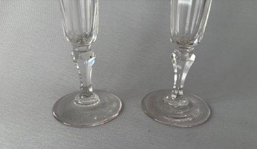 fig 1. A pair of clear early Victorian cut glass champagne flutes featuring flared rims, faceted stems, and slice-cut lower bowls on flat circular bases.