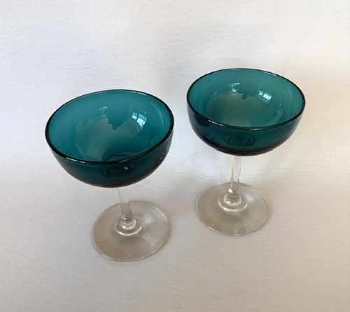 fig 1. A pair of Victorian champagne coupes featuring deep teal green shallow bowls resting on clear glass stems and circular bases.