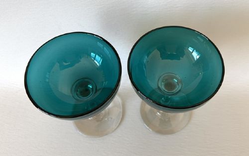 A pair of Victorian champagne coupes featuring deep teal green shallow bowls resting on clear glass stems and circular bases. View V
