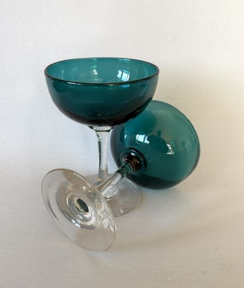 A pair of Victorian champagne coupes featuring deep teal green shallow bowls resting on clear glass stems and circular bases. View VI