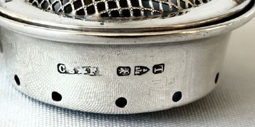A late Victorian silver tea infuser featuring a circular mesh cage connected to a stem with a light-coloured carved handle. View V