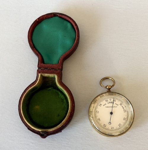 fig 1. An Edwardian brass pocket barometer and altimeter displayed inside an open plush-lined maroon leather case.