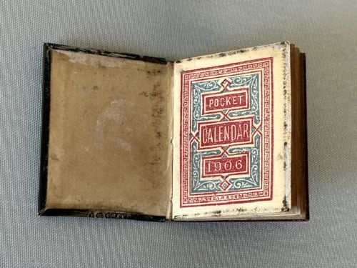 A miniature Edwardian book-shaped pocket calendar featuring an embossed silver front cover with detailed scrollwork and a central latticework pattern. View III