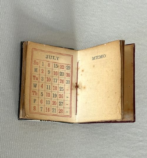 A miniature Edwardian book-shaped pocket calendar featuring an embossed silver front cover with detailed scrollwork and a central latticework pattern. View IV