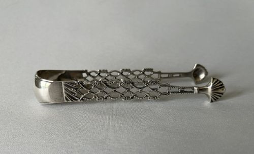fig 1. A pair of 18th-century cast silver sugar tongs featuring openwork lattice arms and shell-shaped grips.