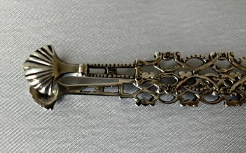 A pair of 18th-century cast silver sugar tongs featuring openwork lattice arms and shell-shaped grips. View IV