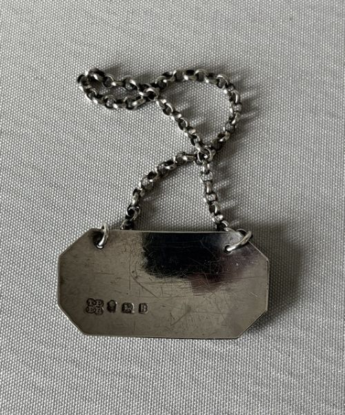 An 18th-century octagonal silver decanter label engraved with HOLLANDS suspended by a silver chain. View IV