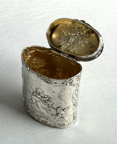 An early nineteenth-century Dutch silver miniature tea caddy featuring relief repousse scenes of classical figures on an oval body with a fitted lid. View V