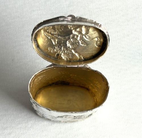 An early nineteenth-century Dutch silver miniature tea caddy featuring relief repousse scenes of classical figures on an oval body with a fitted lid. View VI