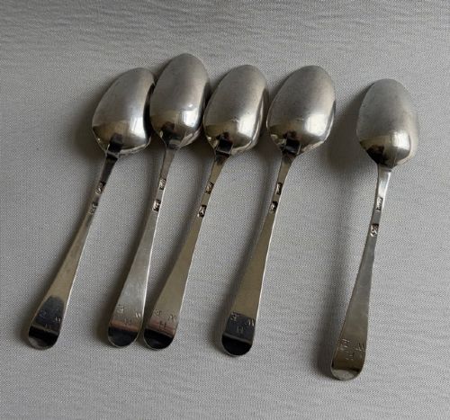 A set of five sterling silver teaspoons arranged in a fan shape showing plain stems and oval bowls. View III