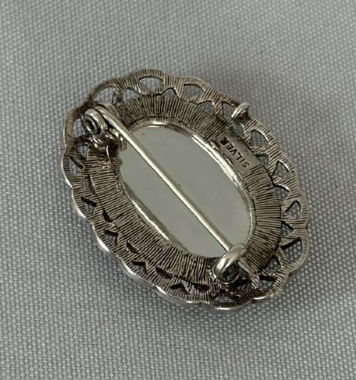 An oval Art Deco silver brooch featuring a polished Blue John stone with purple and yellow banding, encircled by a textured scalloped lattice border. View IV