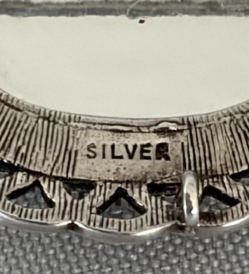 An oval Art Deco silver brooch featuring a polished Blue John stone with purple and yellow banding, encircled by a textured scalloped lattice border. View V