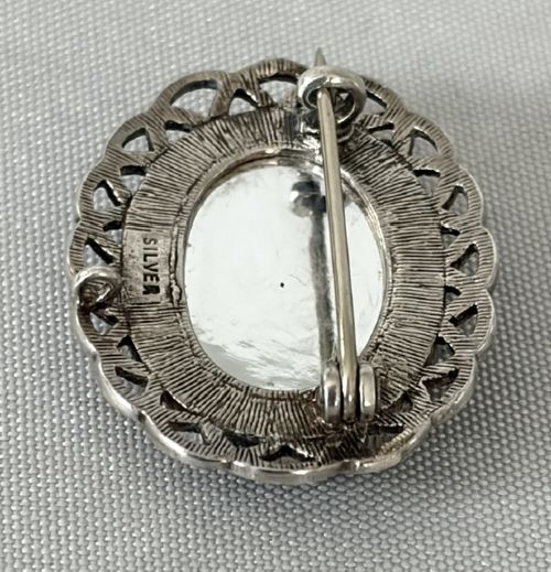 An oval Art Deco silver brooch featuring a polished Blue John stone with purple and yellow banding, encircled by a textured scalloped lattice border. View VI