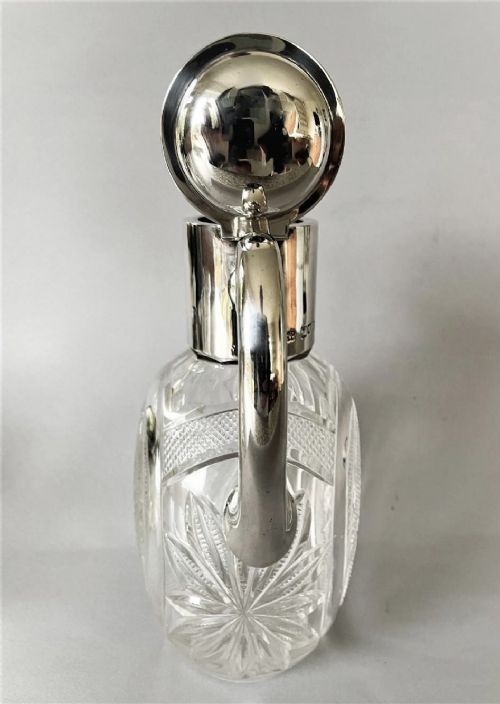 fig 1. A Victorian silver-mounted cut glass claret jug featuring a globular body with starburst facets, a hinged lid, and a smooth silver handle.