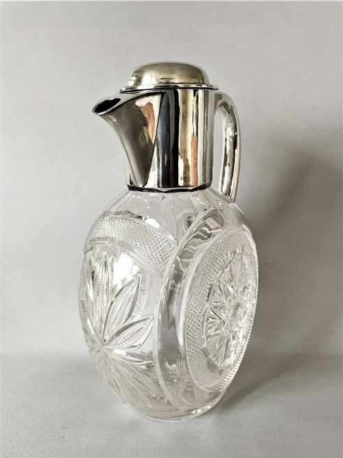 A Victorian silver-mounted cut glass claret jug featuring a globular body with starburst facets, a hinged lid, and a smooth silver handle. View VIII