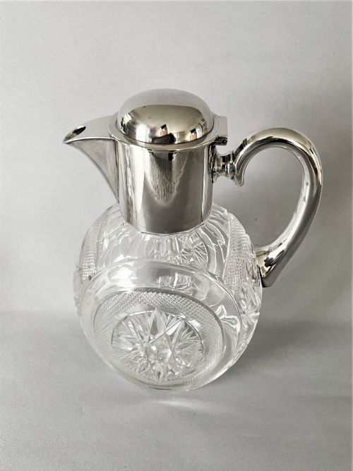A Victorian silver-mounted cut glass claret jug featuring a globular body with starburst facets, a hinged lid, and a smooth silver handle. View IX