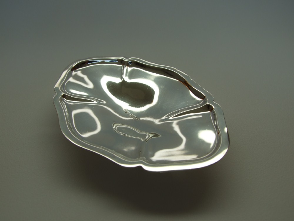 A delightful Edwardian shaped silver trinket dish on four cast feet.