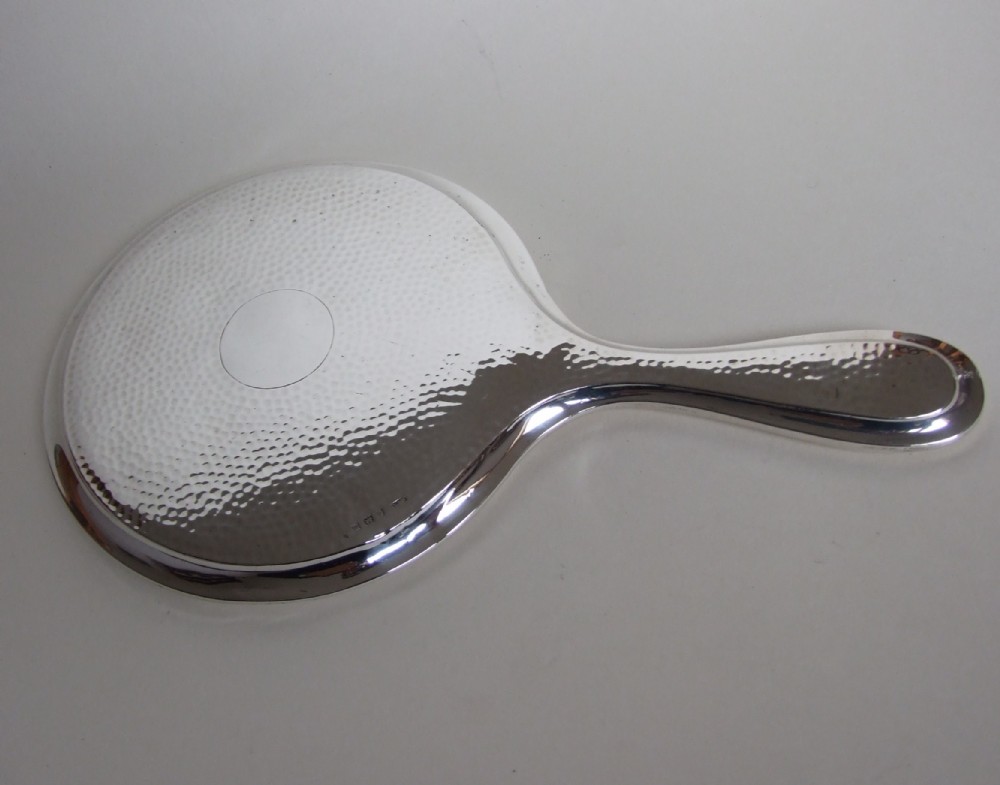 A stylish hammered silver hand mirror in the Arts & Crafts style.