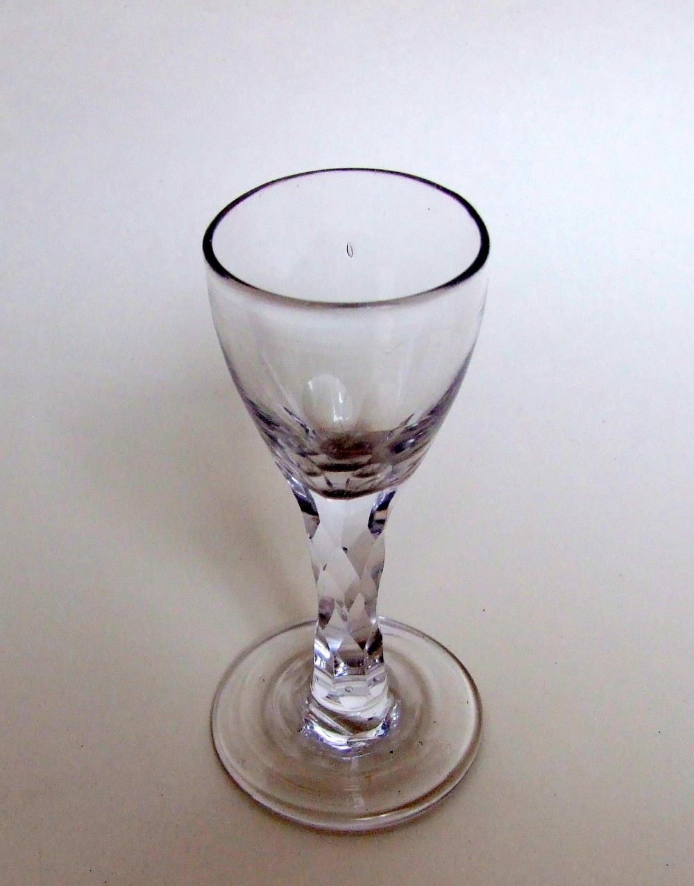 An 18th Century cordial glass with facet cut stem.