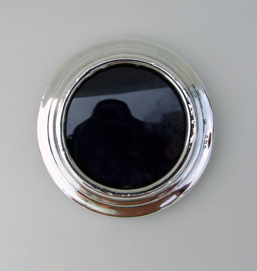 A small silver photo frame of circular form.