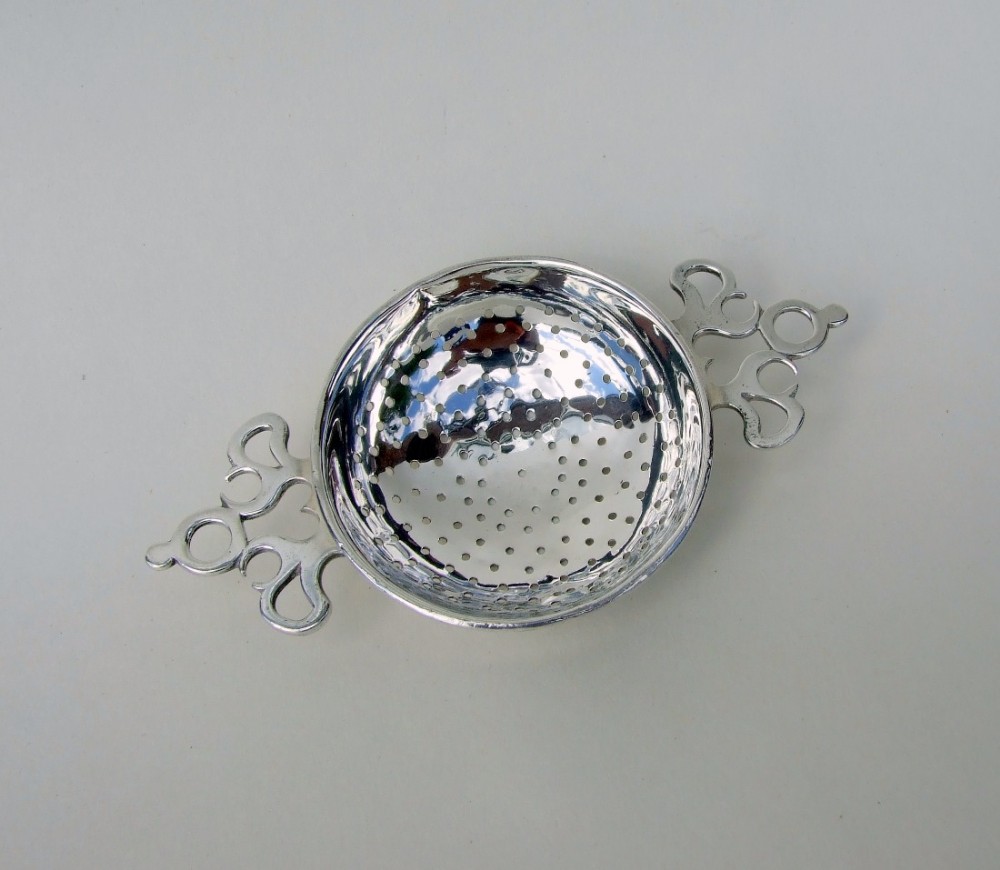 A gorgeous George V silver tea strainer.