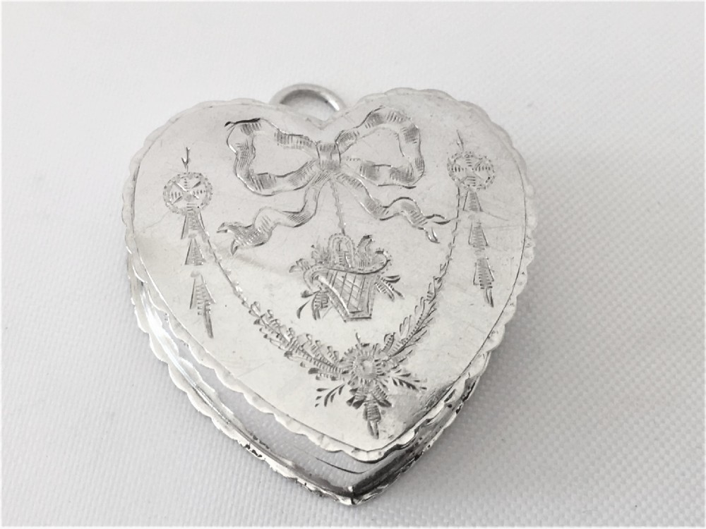 An engraved silver heart shaped pillbox.