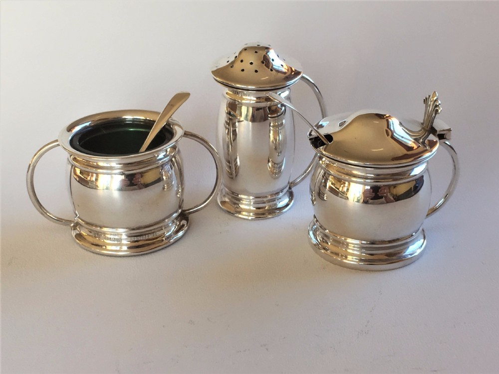 A stylish silver cruet with green liners and spoons