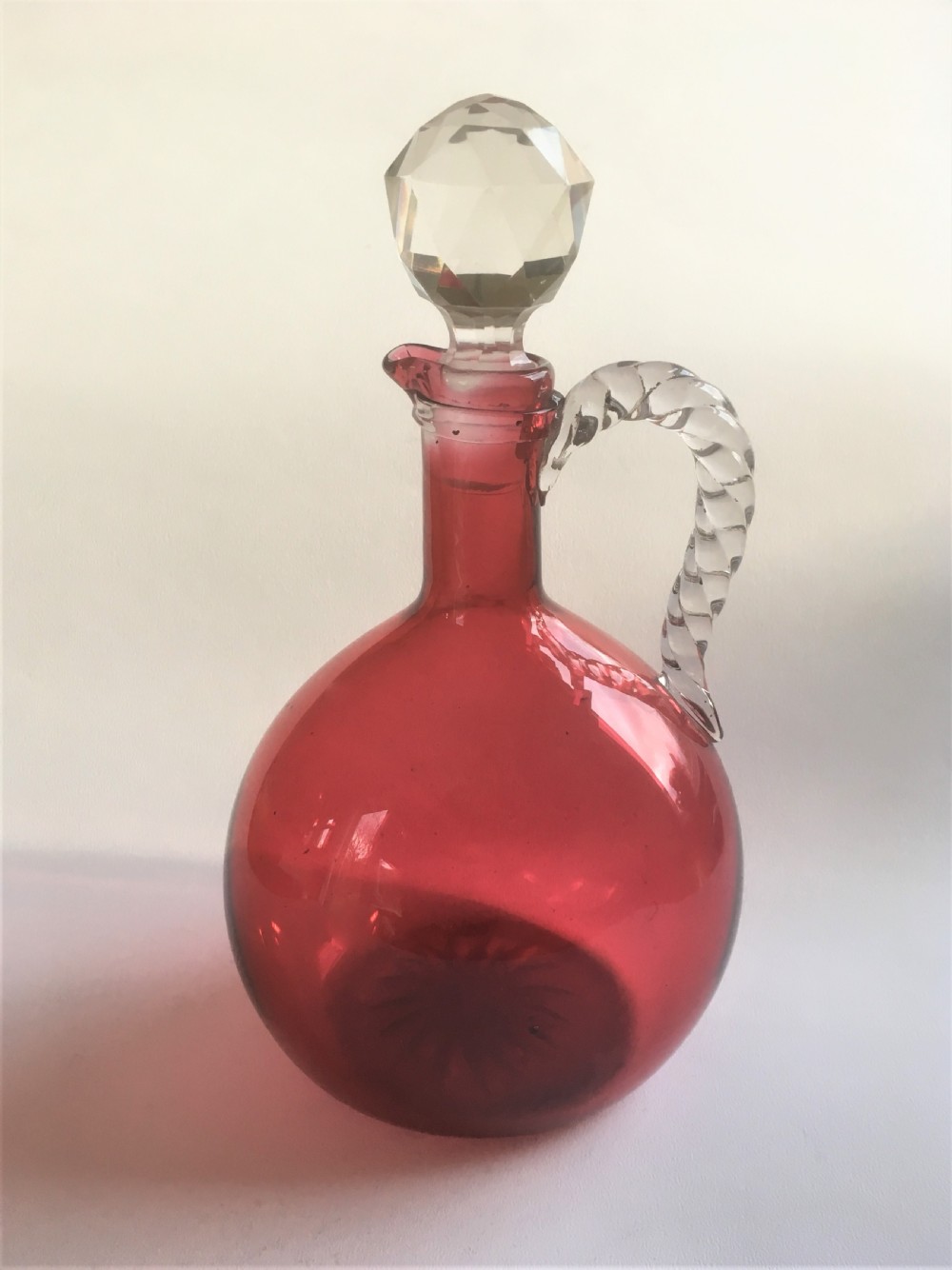 A Victorian cranberry wine jug with barley twist handle