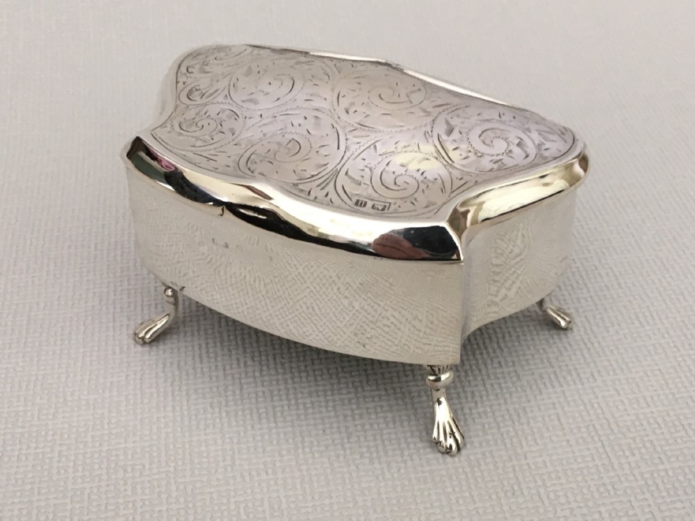 A shaped silver trinket box with engraved decoration