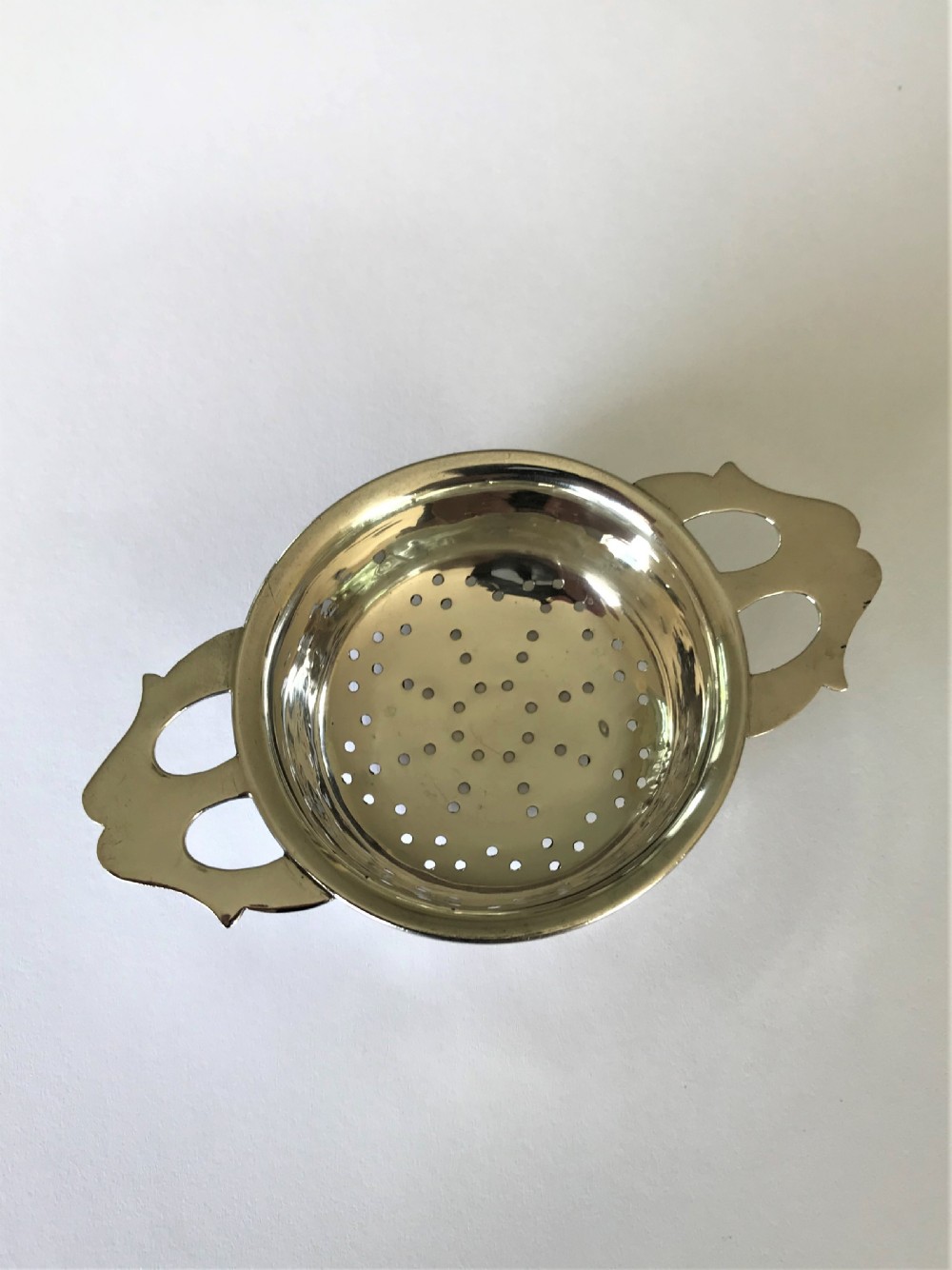 A stylish silver tea strainer in the Art Nouveau style