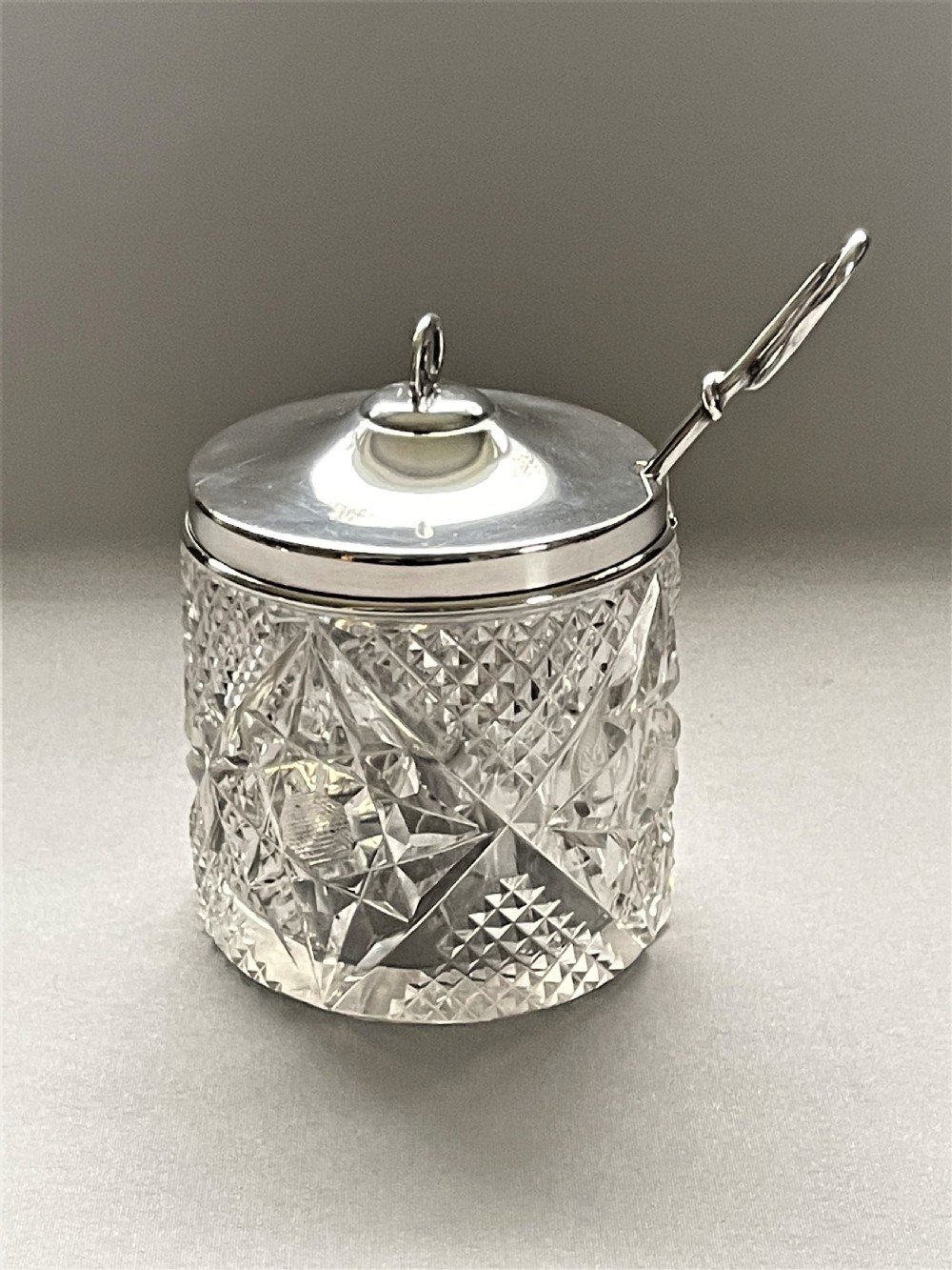 An Edwardian silver mounted cut glass preserve jar & spoon