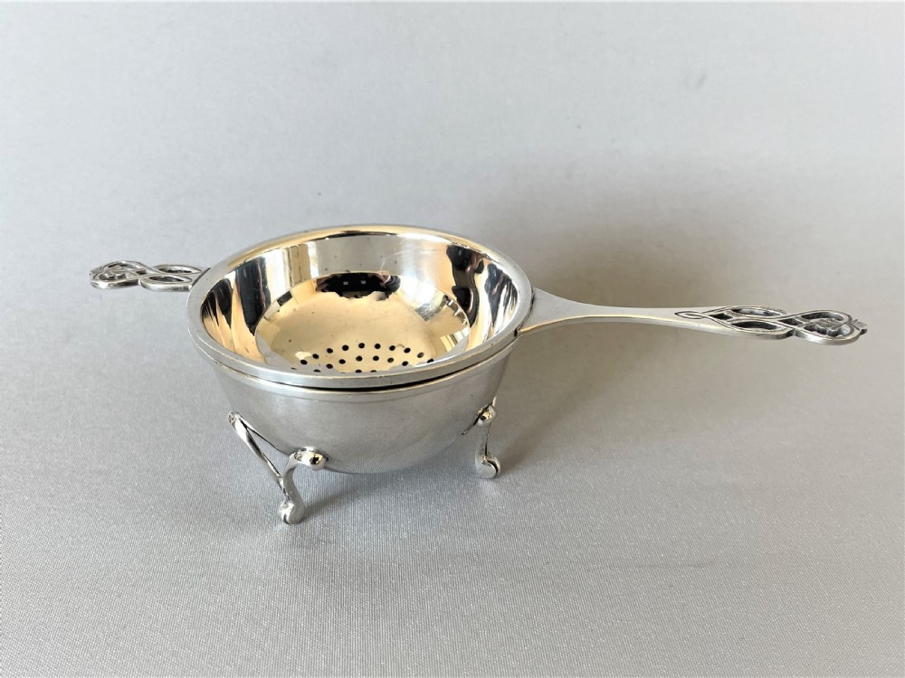 A handsome silver tea strainer & matching drip cup