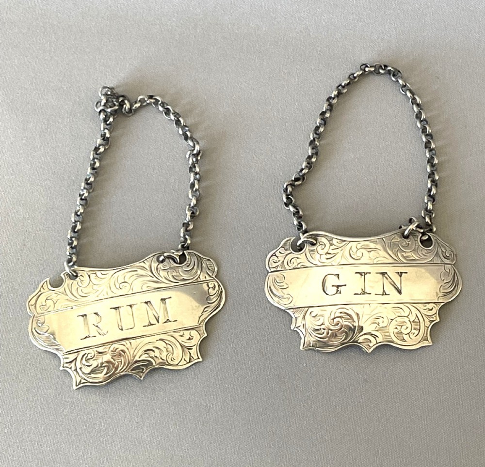 A desirable pair of Victorian silver Rum & Gin decanter labels