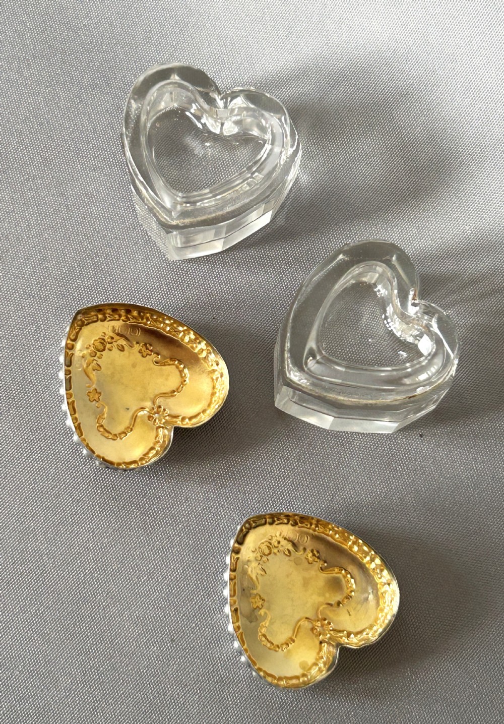 A pair of heart-shaped clear cut glass vanity jars featuring chased sterling silver lids with floral motifs. View IV