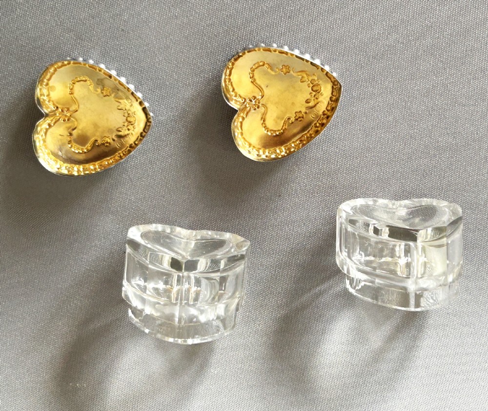 A pair of heart-shaped clear cut glass vanity jars featuring chased sterling silver lids with floral motifs. View V
