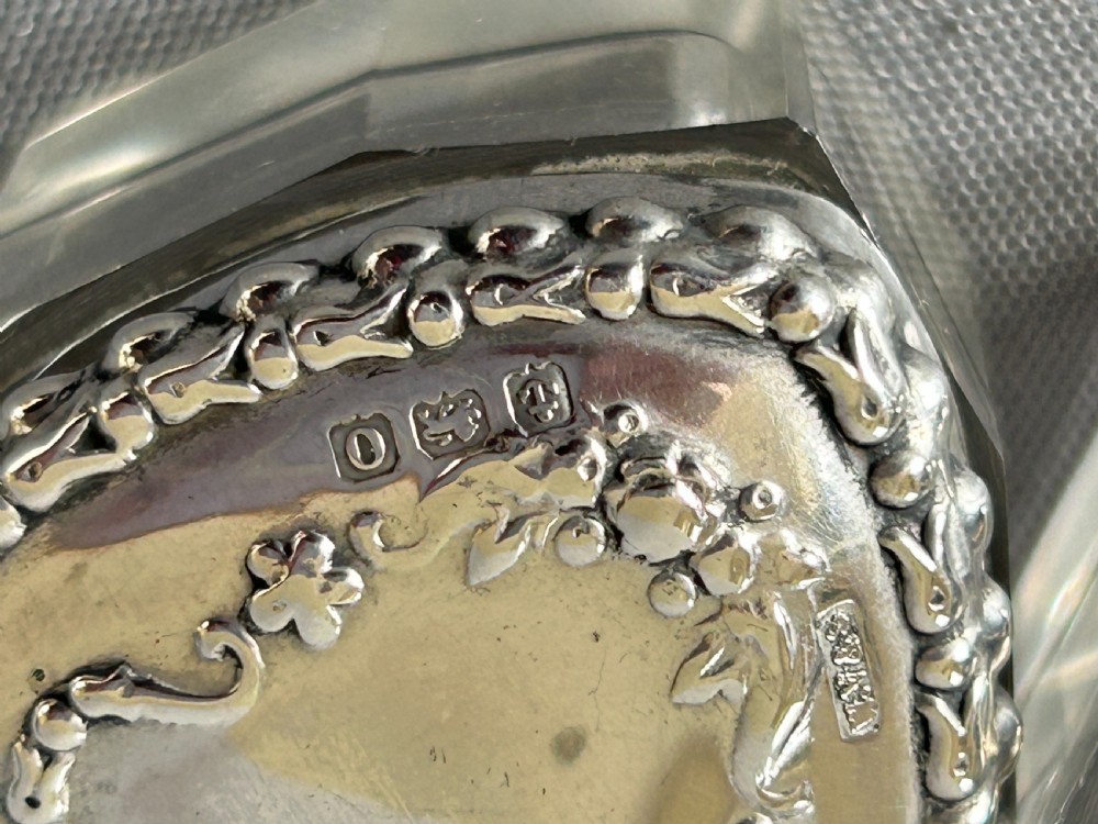 A pair of heart-shaped clear cut glass vanity jars featuring chased sterling silver lids with floral motifs. View VI