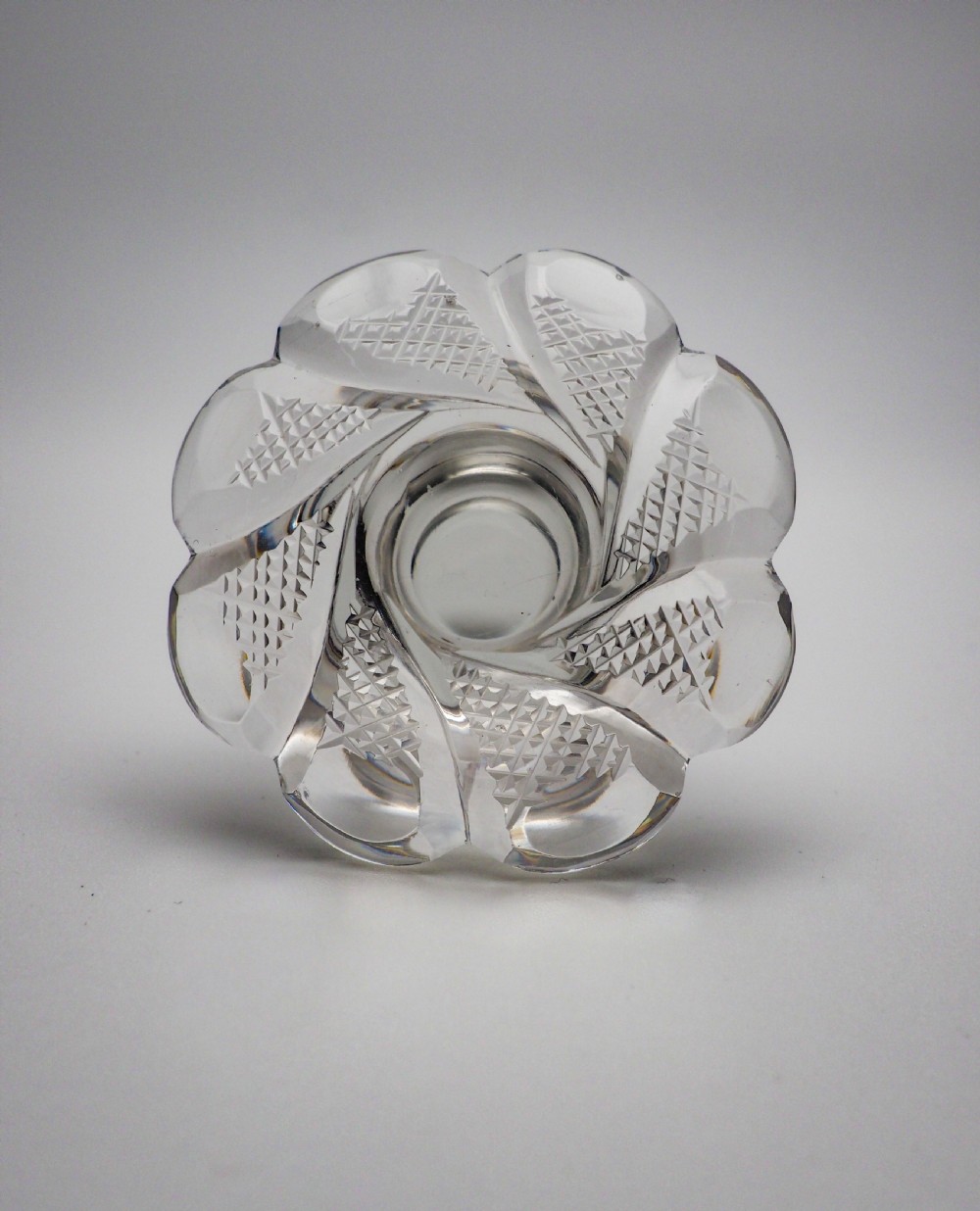 An Early Victorian clear cut glass spirit decanter featuring deep geometric cutting, a fluted base, and a flat faceted stopper. View XI