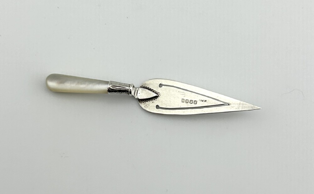 A trowel-shaped sterling silver page clip featuring a carved mother-of-pearl handle and stamped Glasgow hallmarks on the blade.