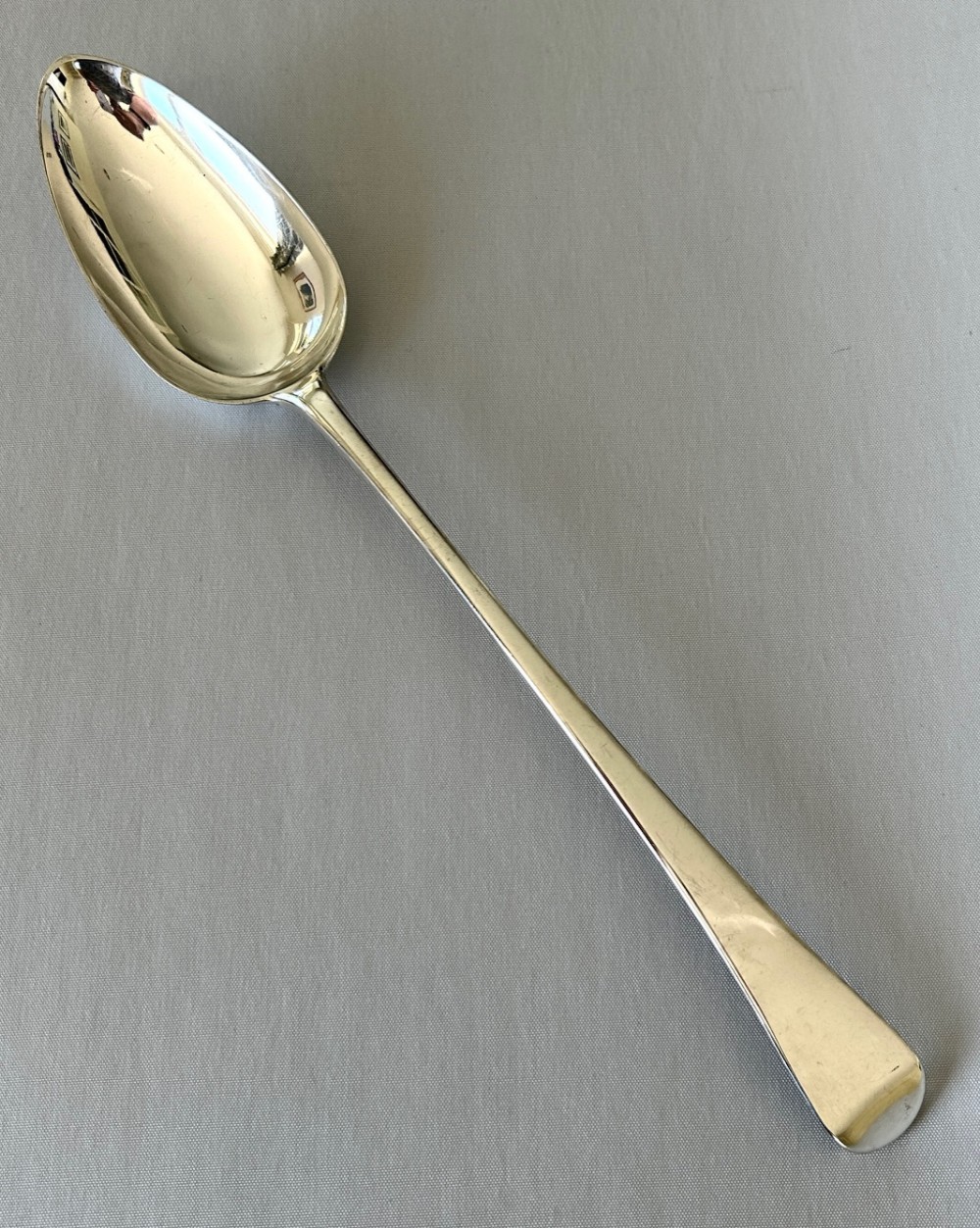 An 18th-century sterling silver basting spoon with a deep oval bowl and a long tapered handle.