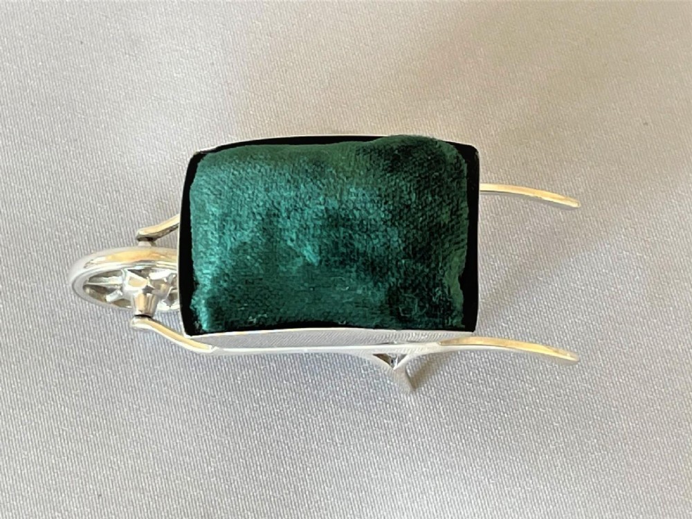 An Edwardian sterling silver pin cushion in the shape of a miniature wheelbarrow with a dark green velvet insert. View V